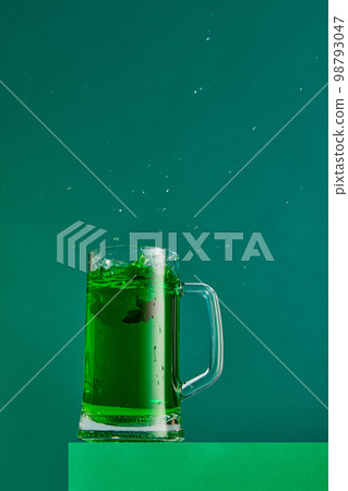 Extraordinary taste. Mug with green beer and anis isolated over green background. Concept of st patrick's day celebration, brewery, traditions Extraordinary taste. Mug with green beer and anis isolated over green background. Concept of st patrick's day celebration, brewery, traditions 98793047