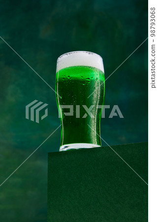 Festival drink. Glass of foamy frothy green beer over dark green background. Traditional hop taste. Concept of st patrick's day celebration, brewery, traditions, 98793068
