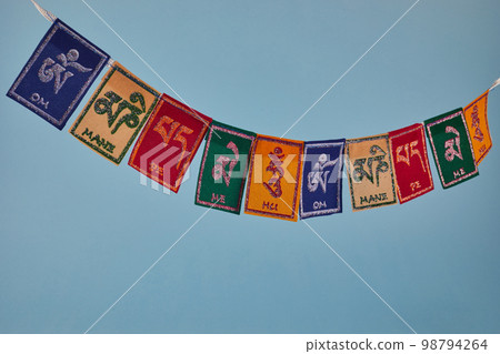 Tibetan Buddhist flags against blue background. Text on flags Om mani padme hum meaning The jewel is in the lotus. 98794264