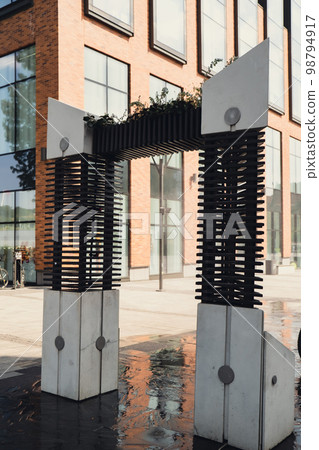 Water spray system for cooling in public place street at the boiling hot summer day. Water mist sprays from arch to alleviate summer heat. Air cooling system with water vapor. Heat global warming  98794917