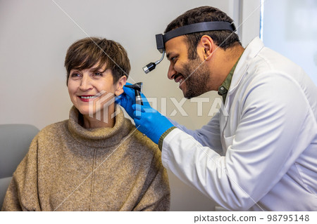 ENT doctor examinine patients ear with endoscope 98795148