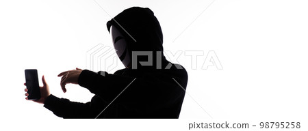 Hacker Anonymous and face mask with smartphone in hand. Man in black hood shirt holding and using mobile phone on white background. Represent cyber crime data hacking or stealing personal data concept 98795258