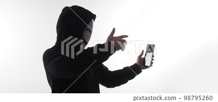 Hacker Anonymous and face mask with smartphone in hand. Man in black hood shirt holding and using mobile phone on white background. Represent cyber crime data hacking or stealing personal data concept 98795260
