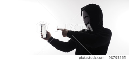 Hacker Anonymous and face mask with smartphone in hand. Man in black hood shirt holding and using mobile phone on white background. Represent cyber crime data hacking or stealing personal data concept 98795265