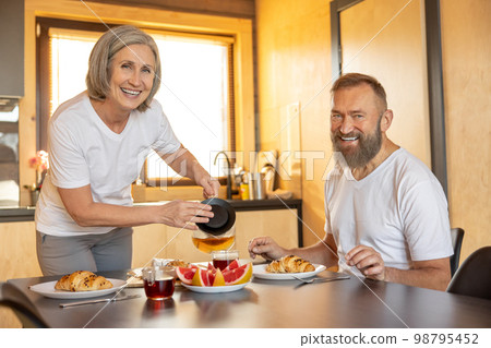 Happy couple having breakfast and feeling comfortable Happy couple having breakfast and feeling comfortable 98795452