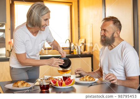 Happy couple having breakfast and feeling comfortable Happy couple having breakfast and feeling comfortable 98795453