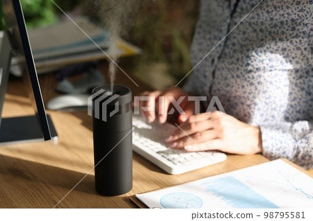 Electronic air humidifier on the desk of an office employee 98795581