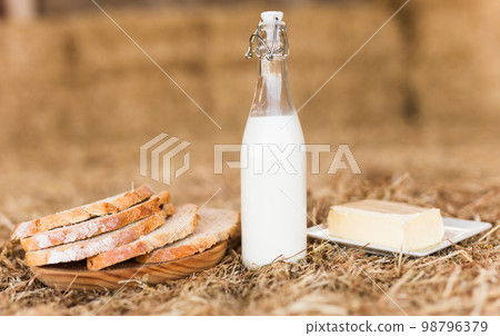 Rustic breakfast of milk, fresh wheat bread and butter in the hayloft 98796379