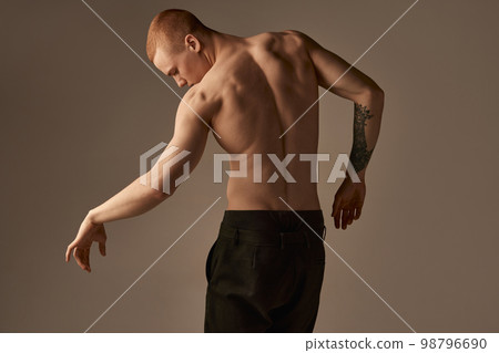 Portrait of handsome young redhead man posing shirtless in pants over grey studio background. Muscular body shape. Relief back. Men's health, beauty and sportive lifestyle 98796690