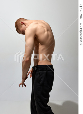 Round back. Masculinity aesthetics. Young man posing shirtless over light grey background. Muscular body shape. Men's health, beauty and sportive lifestyle 98796712