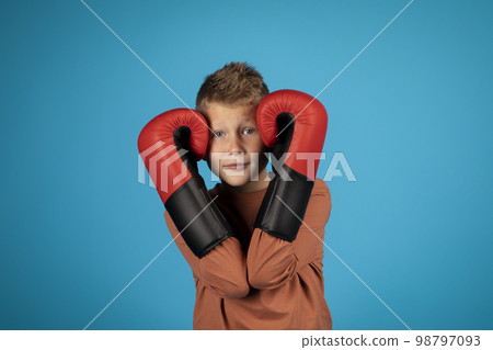 Portrait Of Preteen Blonde Boy Covering Ears With Boxing Gloves 98797093