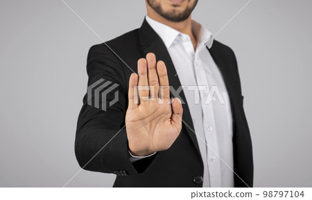 Young Businessman Showing Stop Gesture With Open Palm At Camera Young Businessman Showing Stop Gesture With Open Palm At Camera 98797104