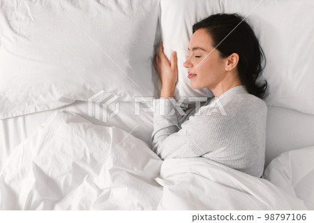 Smiling young european female sleeping on white bed, enjoying good morning, weekend or free time 98797106