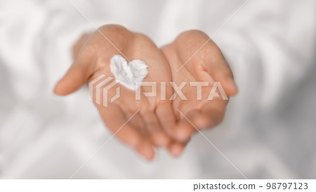 Millennial european woman applying cream on heart shaped on hands, enjoy daily procedures in bedroom Millennial european woman applying cream on heart shaped on hands, enjoy daily procedures in bedroom 98797123