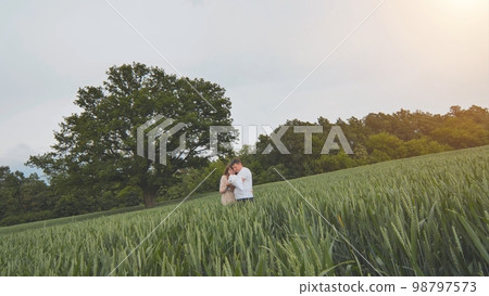 A young couple with their newborn baby in green wheat in a field. A young couple with their newborn baby in green wheat in a field. 98797573