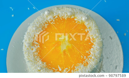 Cake with orange and coconut shavings spinning on a blue background. Cake with orange and coconut shavings spinning on a blue background. 98797589
