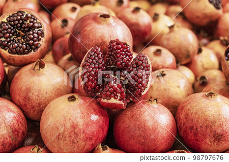 Juicy ripe Pomegranate fruit, Punica granatum. Whole and cut open fruits on display market counter 98797676