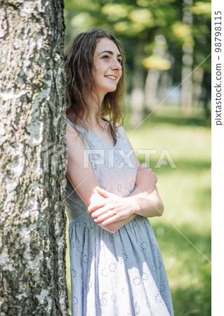 Portrait of a young smiling girl by a birch. 98798115