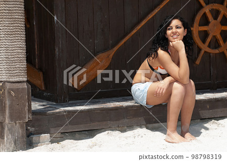 young brunette woman sitting in a hut in a beach or seaside area 98798319