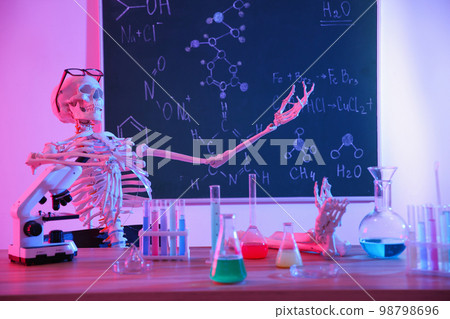 Skeleton and different chemistry glassware in classroom, toned in pink 98798696