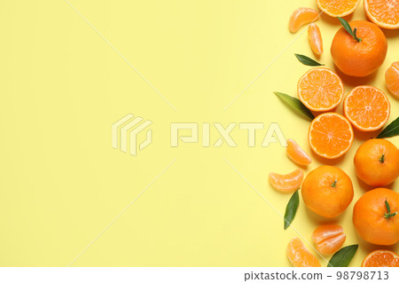 Flat lay composition with fresh ripe tangerines and leaves on light yellow background, space for text. Citrus fruit Flat lay composition with fresh ripe tangerines and leaves on light yellow background, space for text. Citrus fruit 98798713
