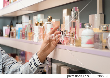 Young woman near shelves with perfume bottles in shop, closeup Young woman near shelves with perfume bottles in shop, closeup 98798852