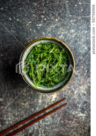 Green seaweed. Japanese wakame salad in bowl. Top view. Green seaweed. Japanese wakame salad in bowl. Top view. 98798906