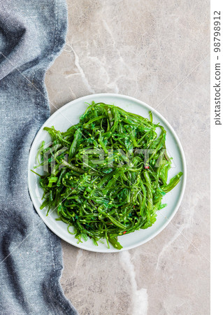Green seaweed. Japanese wakame salad on plate. Top view. Green seaweed. Japanese wakame salad on plate. Top view. 98798912