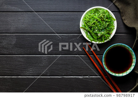 Green seaweed. Japanese wakame salad in bowl and soy sauce. Top view. Green seaweed. Japanese wakame salad in bowl and soy sauce. Top view. 98798917