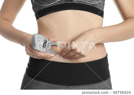Young woman measuring body fat with caliper on white background, closeup Young woman measuring body fat with caliper on white background, closeup 98798920
