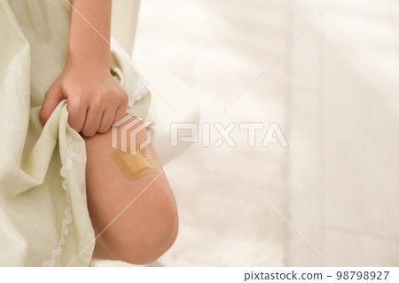 Girl with sticking plaster on leg indoors, closeup 98798927