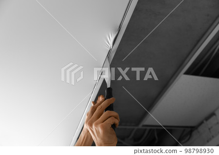 Repairman installing white stretch ceiling in room, closeup 98798930