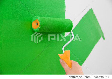 Woman painting white wall with green dye, closeup. Interior renovation 98798957
