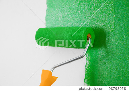 Painting white wall with green dye, closeup. Interior renovation Painting white wall with green dye, closeup. Interior renovation 98798958
