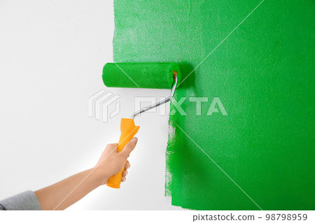 Woman painting white wall with green dye, closeup. Interior renovation 98798959