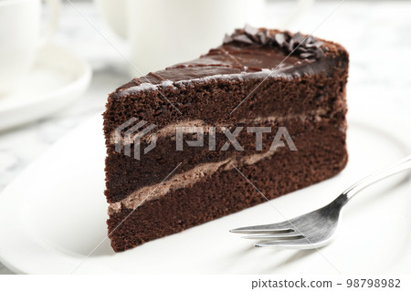 Piece of tasty chocolate cake served on plate 98798982