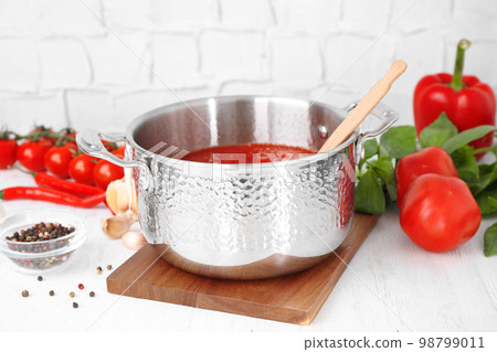 Delicious tomato sauce and fresh ingredients on white wooden table 98799011