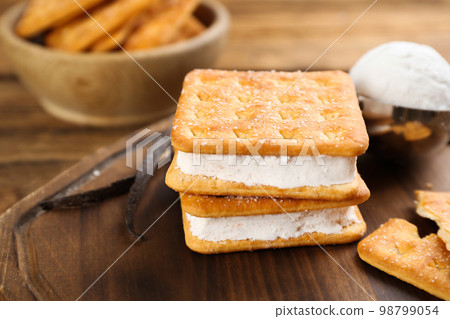 Sweet delicious ice cream cookie sandwiches on wooden board, closeup 98799054