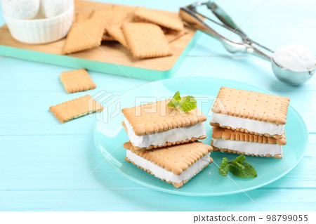 Sweet delicious ice cream cookie sandwiches on light blue wooden table Sweet delicious ice cream cookie sandwiches on light blue wooden table 98799055