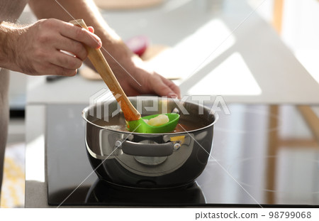 Young man cooking delicious soup in kitchen, closeup Young man cooking delicious soup in kitchen, closeup 98799068