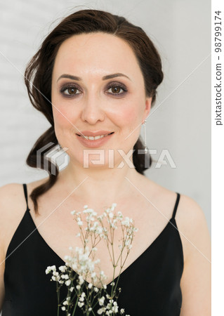 Portrait of friendly young woman holds flowers in living room - spring mood and perfect female make-up concept Portrait of friendly young woman holds flowers in living room - spring mood and perfect female make-up concept 98799174