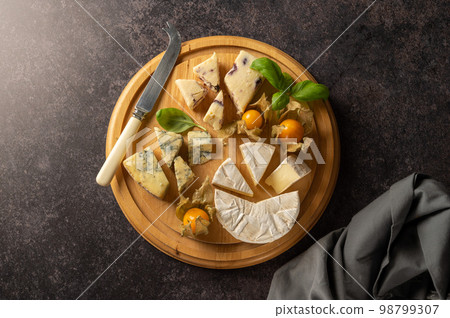 Top view cheese board with blue cheese, cheddar and fruit cheese. Dark background Top view cheese board with blue cheese, cheddar and fruit cheese. Dark background 98799307