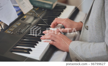 The woman plays the synthesizer. Close-up of her hands. The woman plays the synthesizer. Close-up of her hands. 98799627