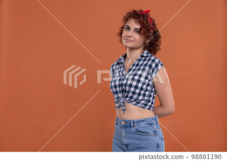 Pin up styling. Girl in short plaid shirt. Curly hair. 98801190