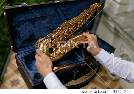 Young musician opening case with saxophone before performance 98801704