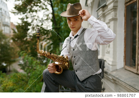 Portrait of young musician holding saxophone musical instrument Portrait of young musician holding saxophone musical instrument 98801707
