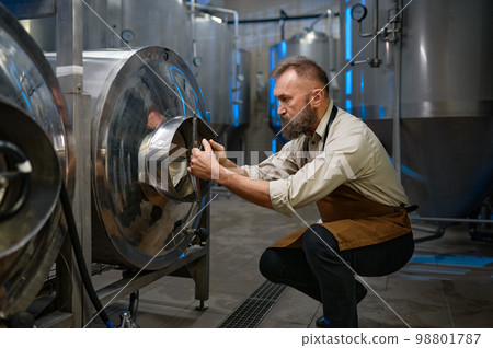Concentrated brewer working with metallic vats in industrial brewery 98801787