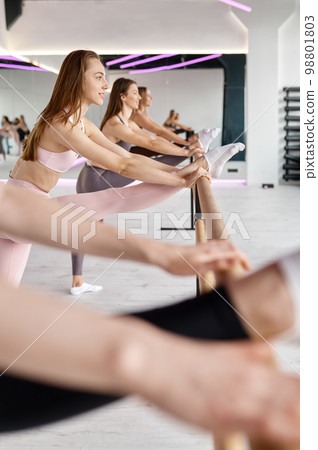 Closeup smiling young woman standing at ballet bar 98801803