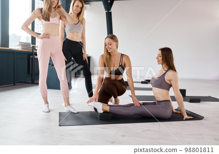 Woman sports coach helping female group with pilates exercises 98801811
