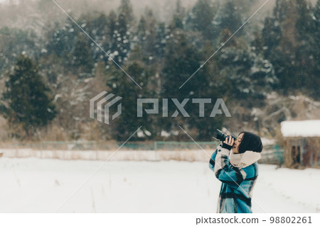 一位年輕女子在雪地裡拿著相機的照片 一位年輕女子在雪地裡拿著相機的照片 98802261